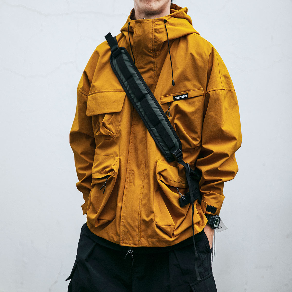 Homme portant une veste jaune à capuche, design urbain moderne.